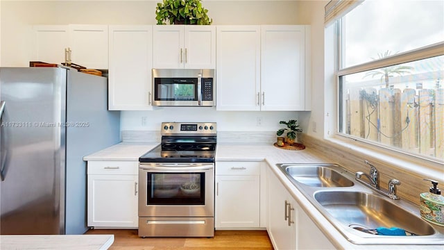 kitchen with white cabinetry, sink, stainless steel appliances, and light wood-type flooring