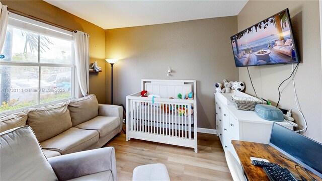 bedroom with light hardwood / wood-style flooring and a crib