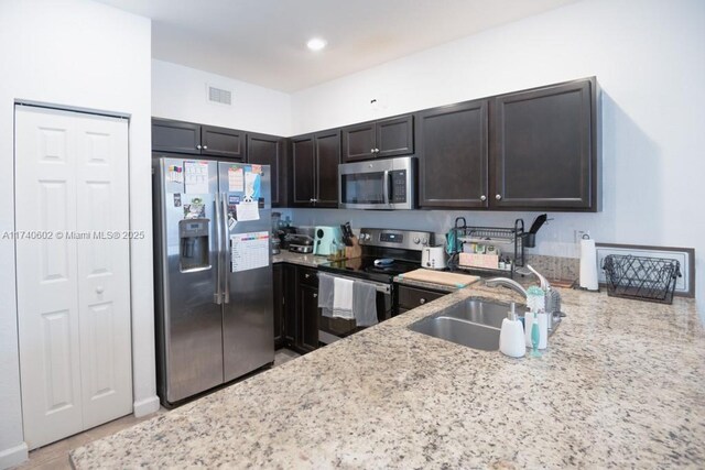 kitchen featuring light stone counters, sink, dark brown cabinets, and appliances with stainless steel finishes