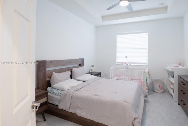 bedroom with ceiling fan and a tray ceiling