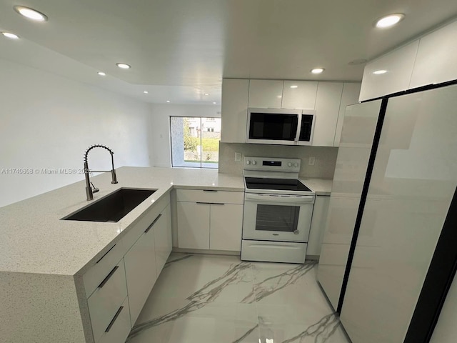 kitchen featuring sink, fridge, white cabinets, white electric stove, and kitchen peninsula