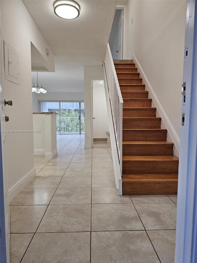 stairs with tile patterned flooring, electric panel, and a textured ceiling