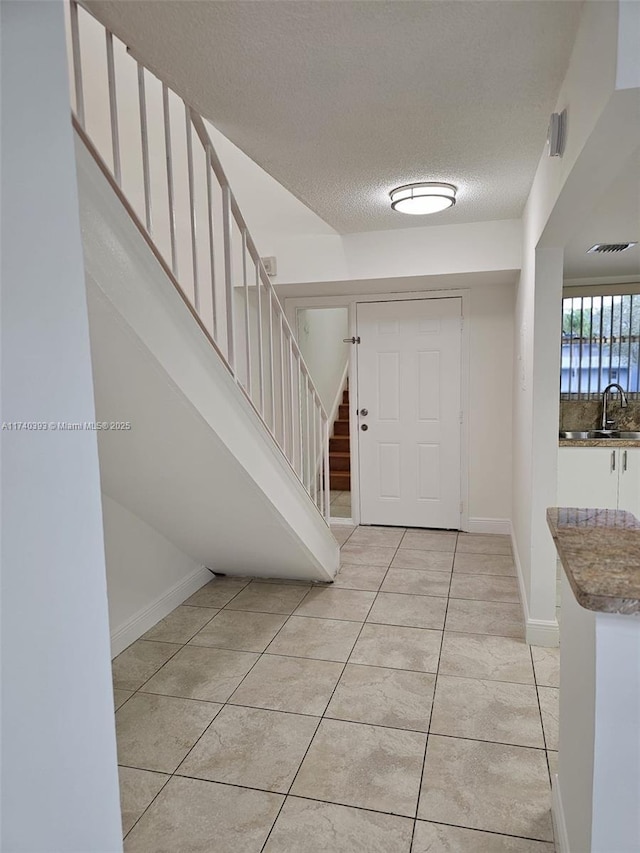 tiled foyer entrance featuring sink and a textured ceiling