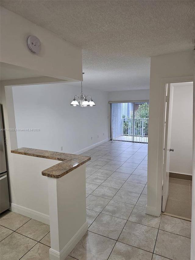 kitchen with a chandelier, hanging light fixtures, light tile patterned floors, kitchen peninsula, and a textured ceiling