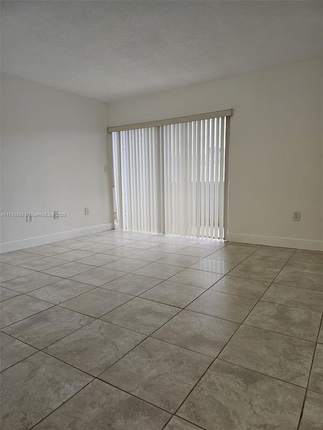 unfurnished room with a textured ceiling and light tile patterned floors