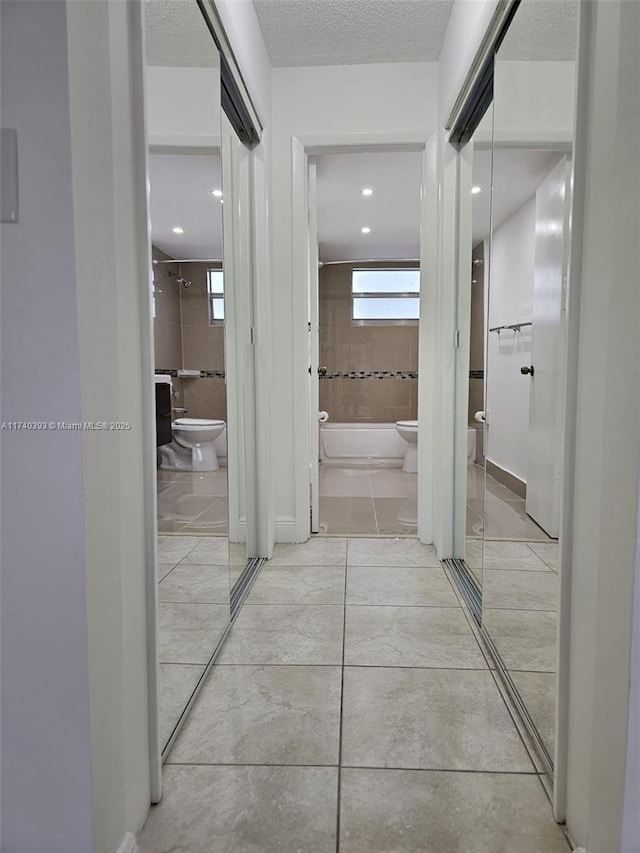 hallway featuring light tile patterned floors and a textured ceiling