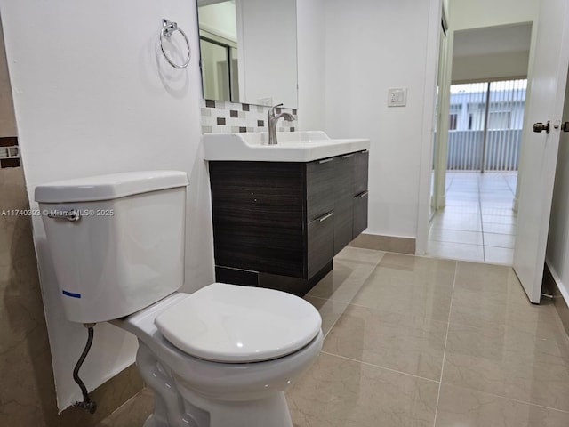 bathroom with tasteful backsplash, vanity, tile patterned flooring, and toilet