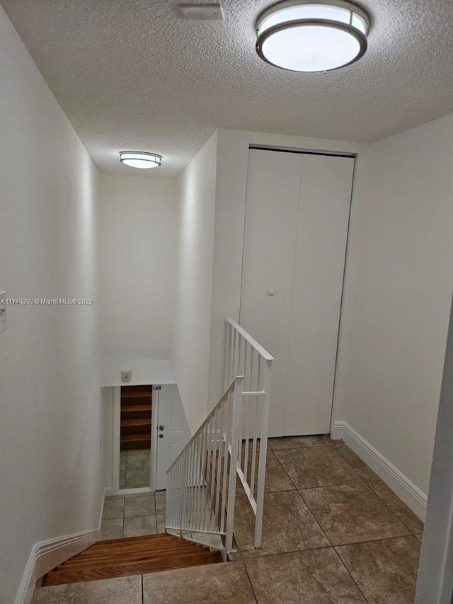 stairway featuring a textured ceiling