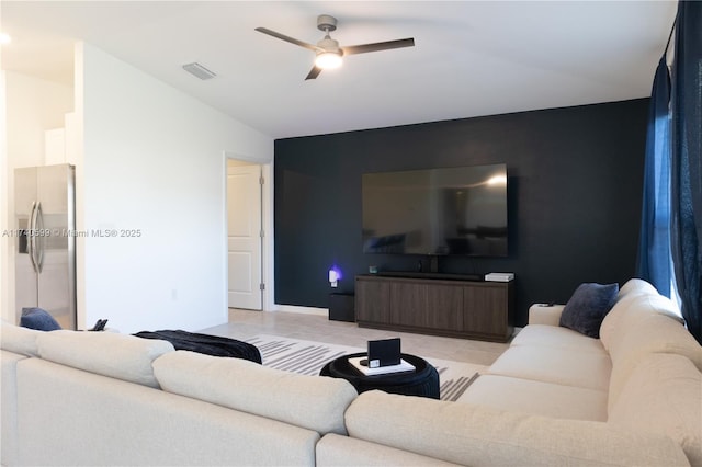 living room featuring light tile patterned floors, visible vents, lofted ceiling, ceiling fan, and an accent wall