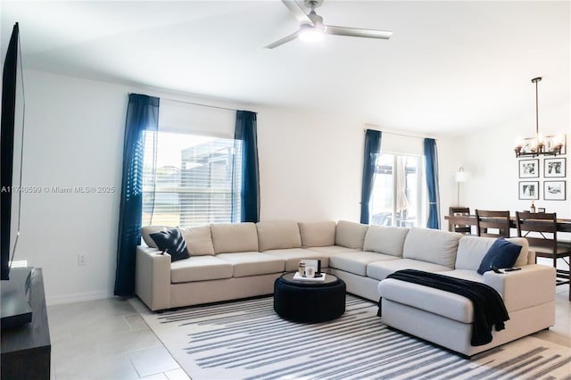 living area featuring light tile patterned floors, ceiling fan with notable chandelier, lofted ceiling, and baseboards