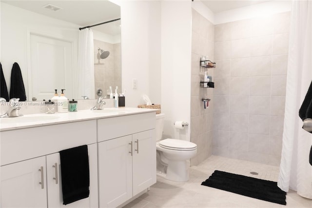 bathroom featuring a tile shower, double vanity, a sink, and visible vents