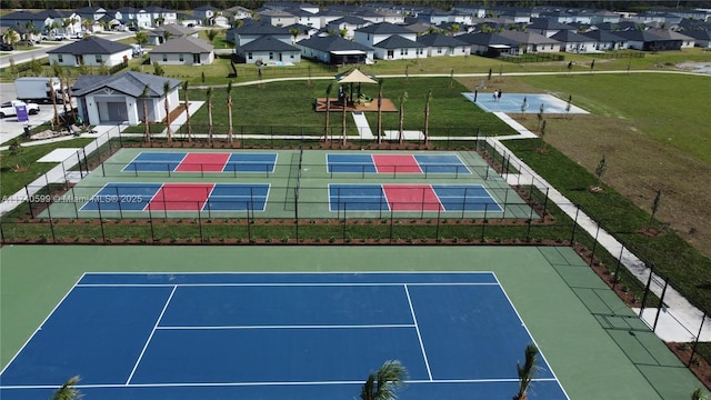 view of tennis court with a residential view and fence