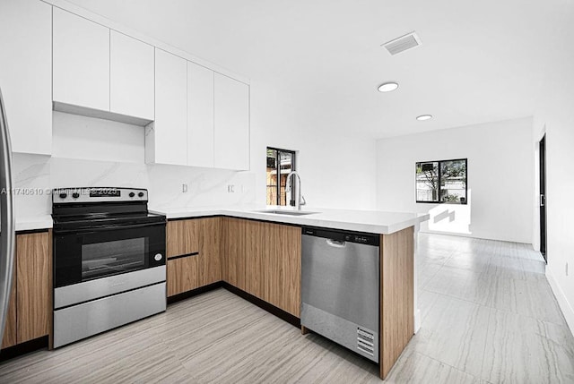 kitchen featuring white cabinetry, appliances with stainless steel finishes, sink, and kitchen peninsula