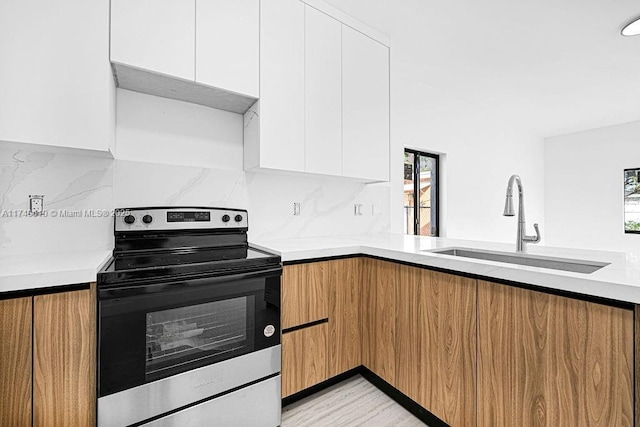 kitchen featuring electric stove, sink, backsplash, and white cabinets