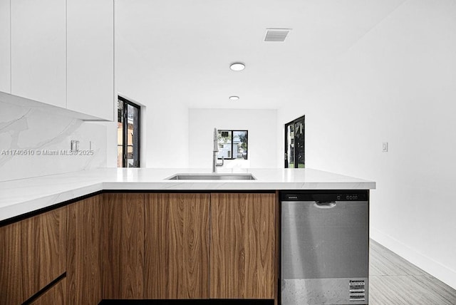 kitchen featuring tasteful backsplash, sink, dishwasher, and white cabinets