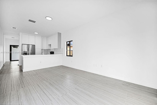 unfurnished living room featuring sink and light wood-type flooring