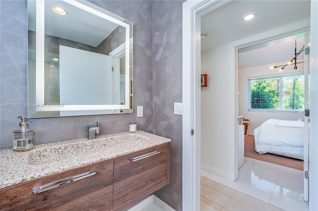 bathroom with tile patterned flooring, baseboards, vanity, a notable chandelier, and recessed lighting