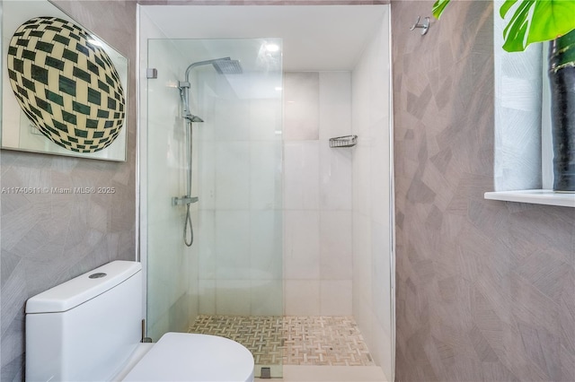 bathroom featuring toilet, tile walls, and a shower stall
