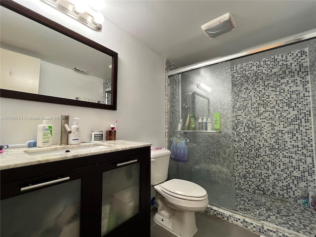 bathroom featuring a shower with door, vanity, and toilet