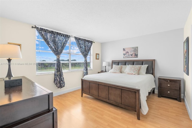 bedroom with light hardwood / wood-style floors and a textured ceiling