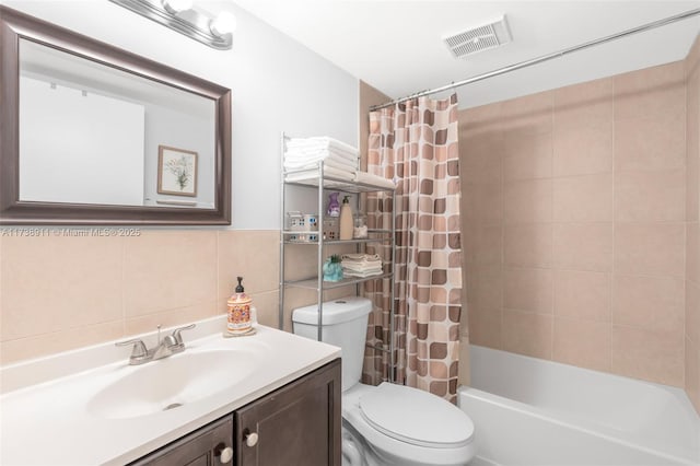 full bathroom featuring vanity, toilet, shower / bath combo with shower curtain, and tile walls