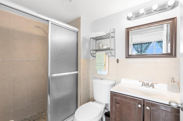 bathroom with tile walls, vanity, a shower with door, and toilet