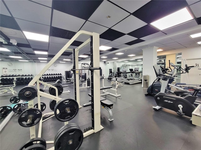 workout area featuring decorative columns and a paneled ceiling