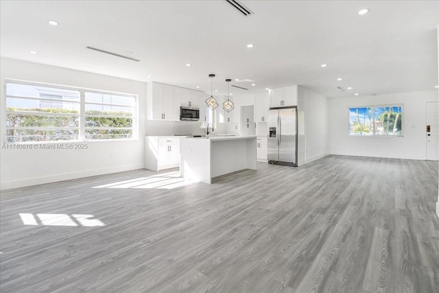 unfurnished living room featuring sink and light hardwood / wood-style floors