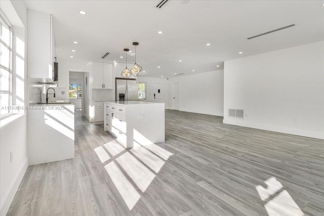 kitchen with sink, white cabinetry, a center island, stainless steel fridge with ice dispenser, and hanging light fixtures