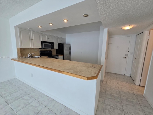 kitchen featuring electric stove, white cabinets, kitchen peninsula, and stainless steel refrigerator