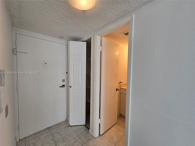 hallway with light tile patterned floors and a textured ceiling