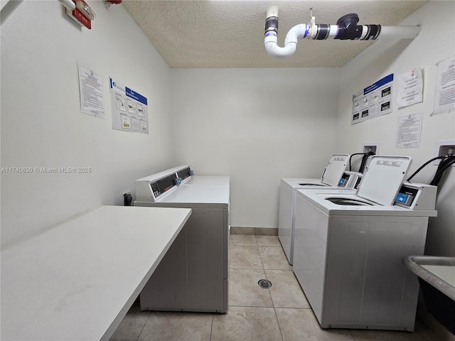 laundry room featuring light tile patterned flooring, washer and dryer, and a textured ceiling