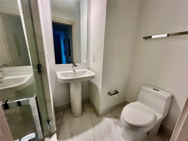 bathroom featuring a shower with door and toilet