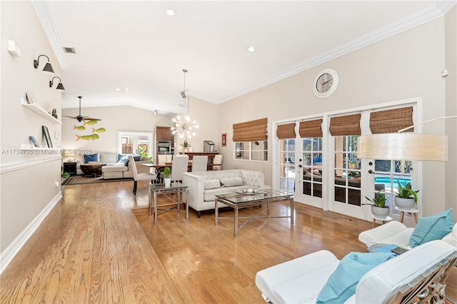 living room with lofted ceiling, ceiling fan with notable chandelier, ornamental molding, and light wood-type flooring