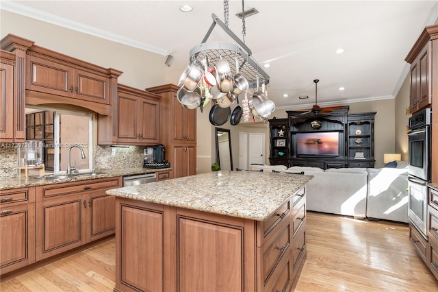 kitchen featuring a kitchen island, sink, decorative backsplash, light stone counters, and crown molding