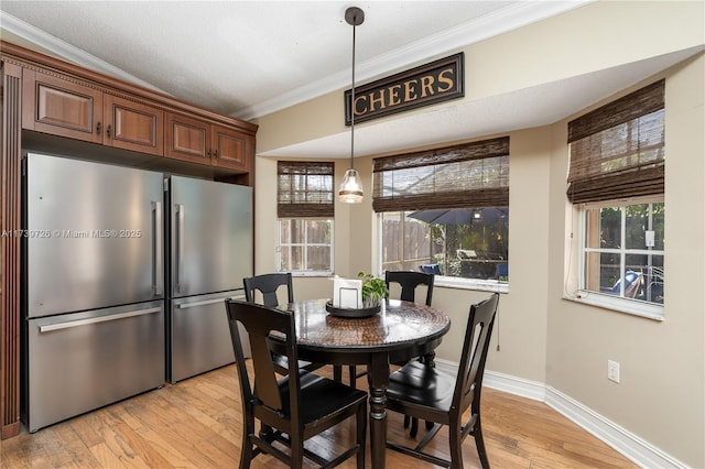 dining area with ornamental molding and light hardwood / wood-style flooring