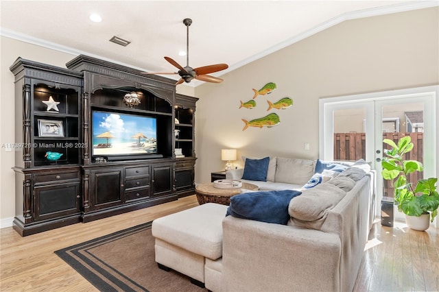 living room featuring french doors, ornamental molding, vaulted ceiling, and light wood-type flooring