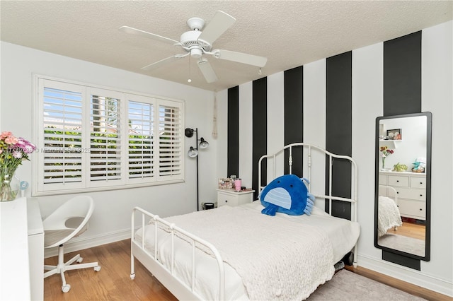 bedroom featuring ceiling fan, wood-type flooring, and a textured ceiling