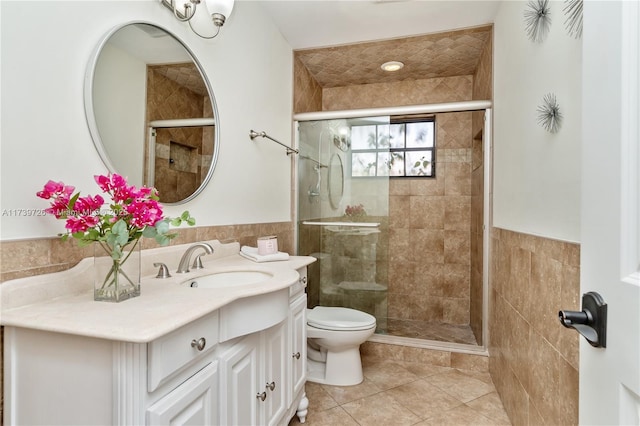 bathroom featuring tile walls, vanity, tile patterned floors, toilet, and walk in shower