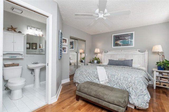 bedroom with connected bathroom, wood-type flooring, a closet, and a textured ceiling