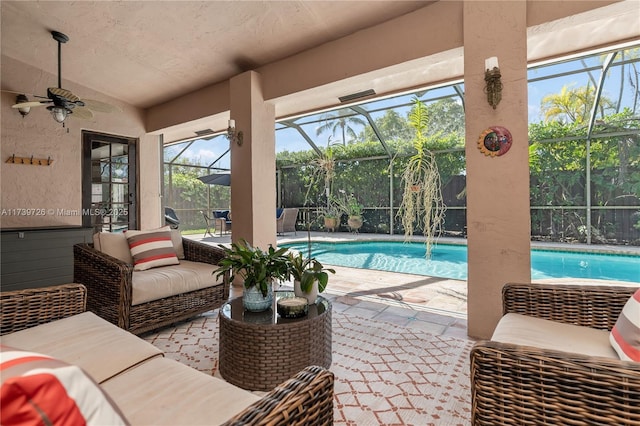 view of pool with an outdoor living space, a patio, ceiling fan, and glass enclosure