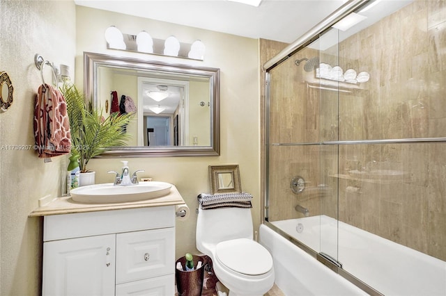 full bath with vanity, toilet, and bath / shower combo with glass door