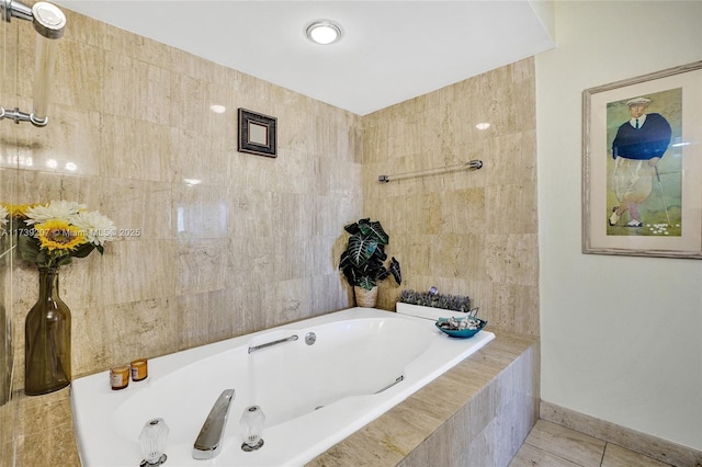 bathroom with baseboards, tiled tub, tile walls, and tile patterned flooring