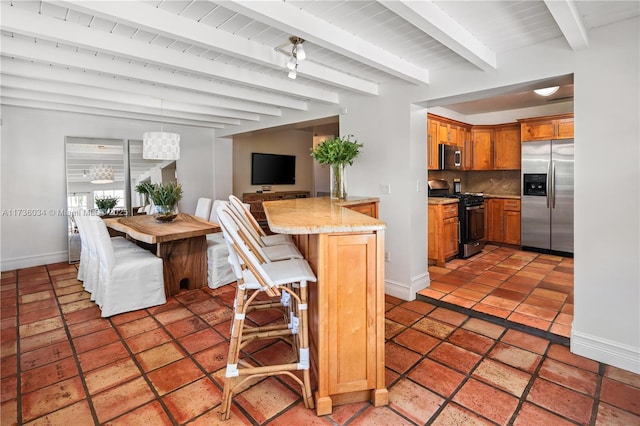 kitchen with a breakfast bar area, appliances with stainless steel finishes, tasteful backsplash, kitchen peninsula, and beamed ceiling