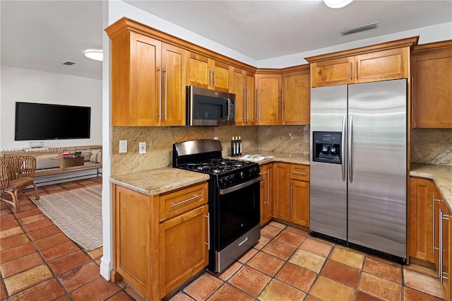 kitchen featuring appliances with stainless steel finishes, backsplash, and light stone counters