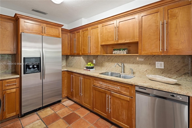 kitchen featuring appliances with stainless steel finishes, sink, light stone counters, and decorative backsplash