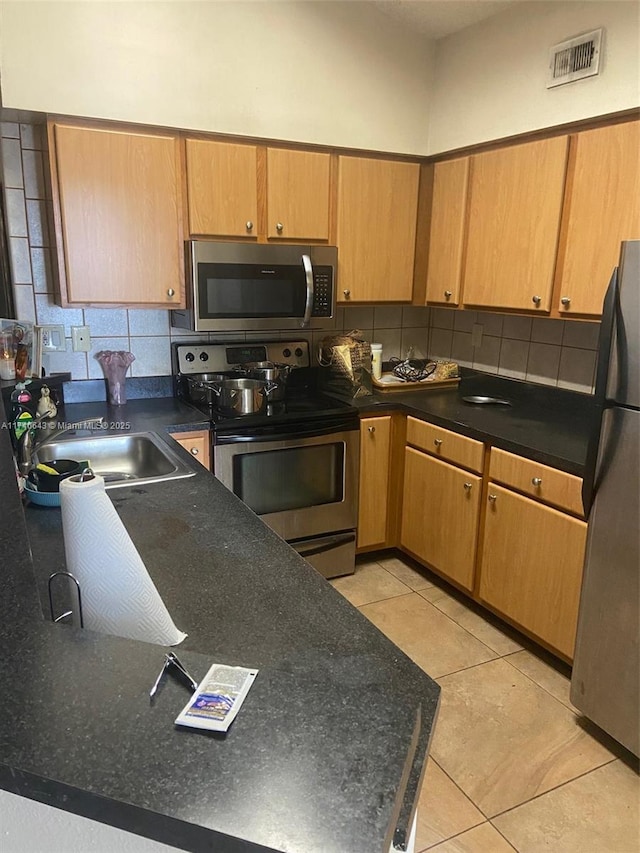 kitchen with appliances with stainless steel finishes, sink, light tile patterned floors, and backsplash