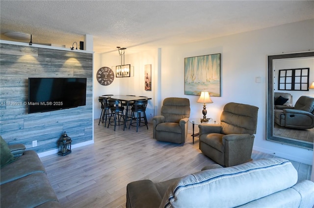 living room with hardwood / wood-style flooring, an inviting chandelier, and a textured ceiling