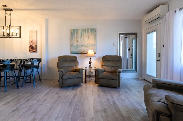 living room featuring a notable chandelier, light hardwood / wood-style floors, and a wall mounted AC