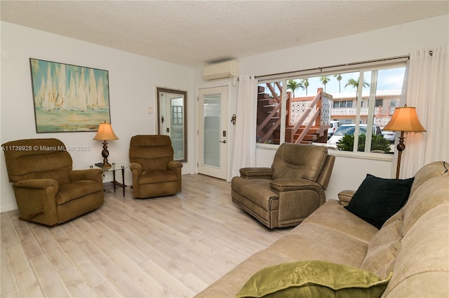 living room featuring wood-type flooring, a wall mounted AC, and a textured ceiling